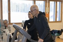 Fysioterapeuttii ohjaa senioria kävelymatolla